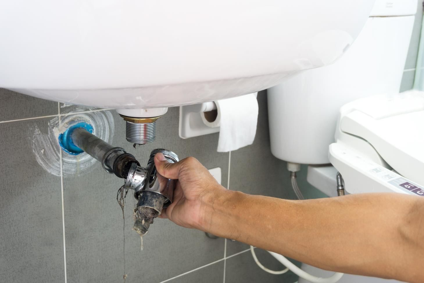 a person is fixing a sink pipe with a pair of pliers