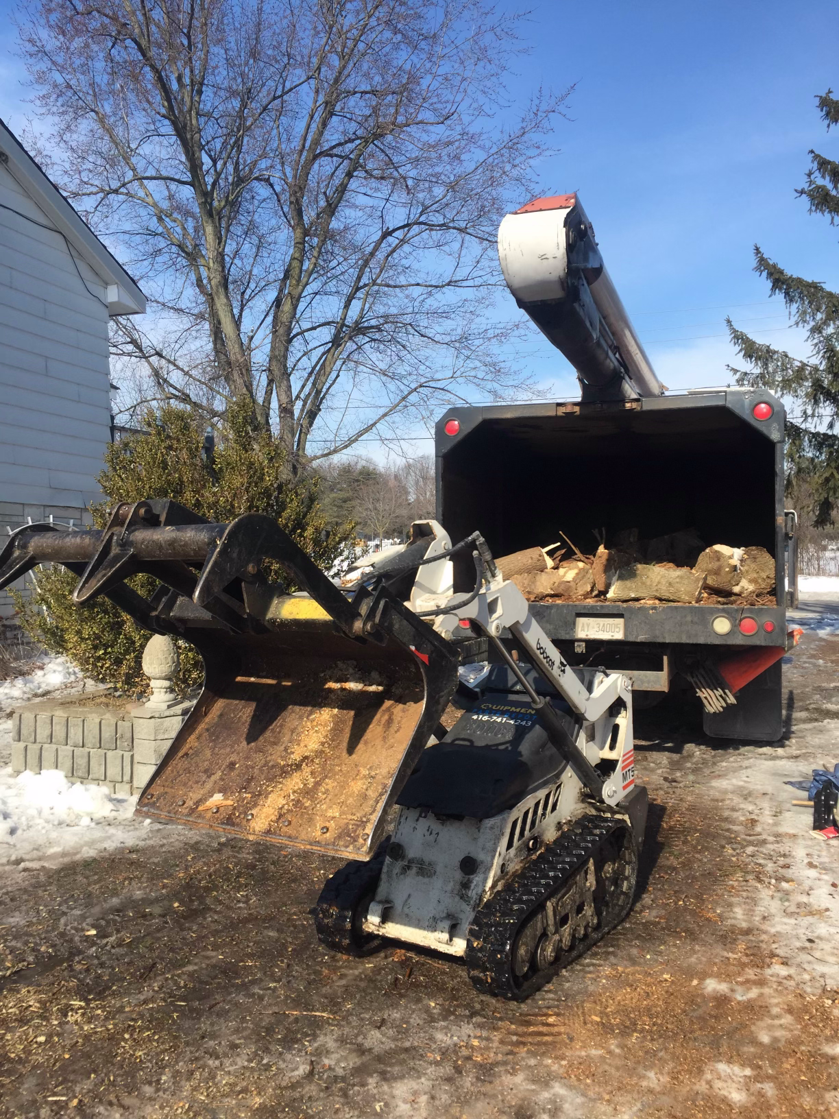 A small bulldozer is loading wood into a truck.