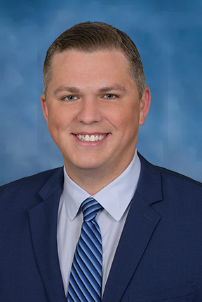 A smiling doctor in a lab coat with a stethoscope around his neck.