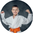 A young boy in a karate uniform is flexing his muscles.