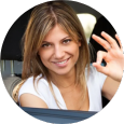 A woman is giving an ok sign while sitting in a car.