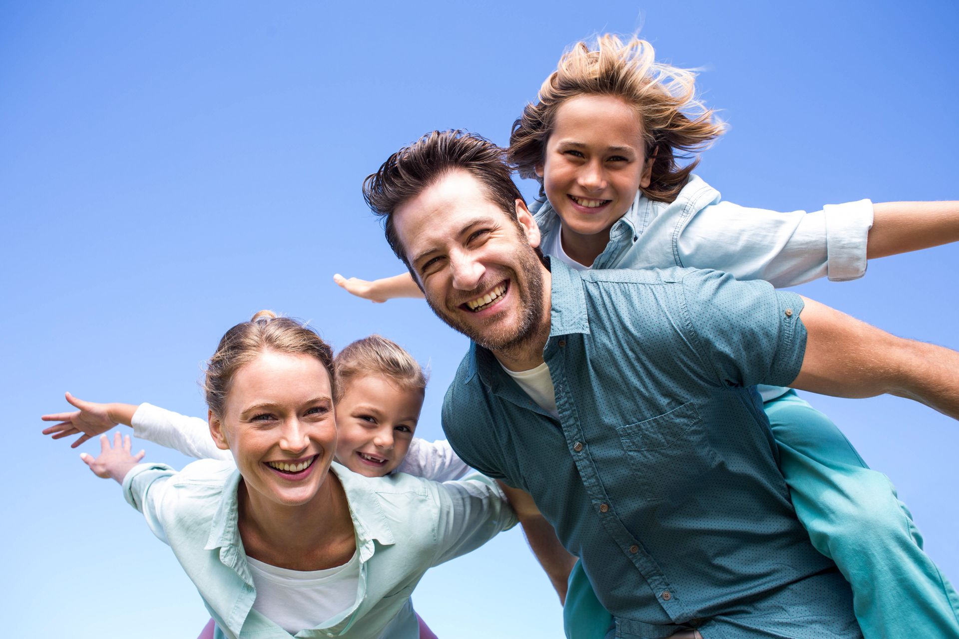 A family is posing for a picture with a blue sky in the background.