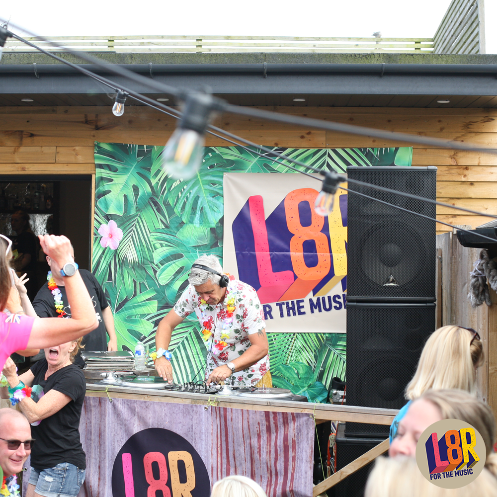 A man is playing music in front of a sign that says l8r