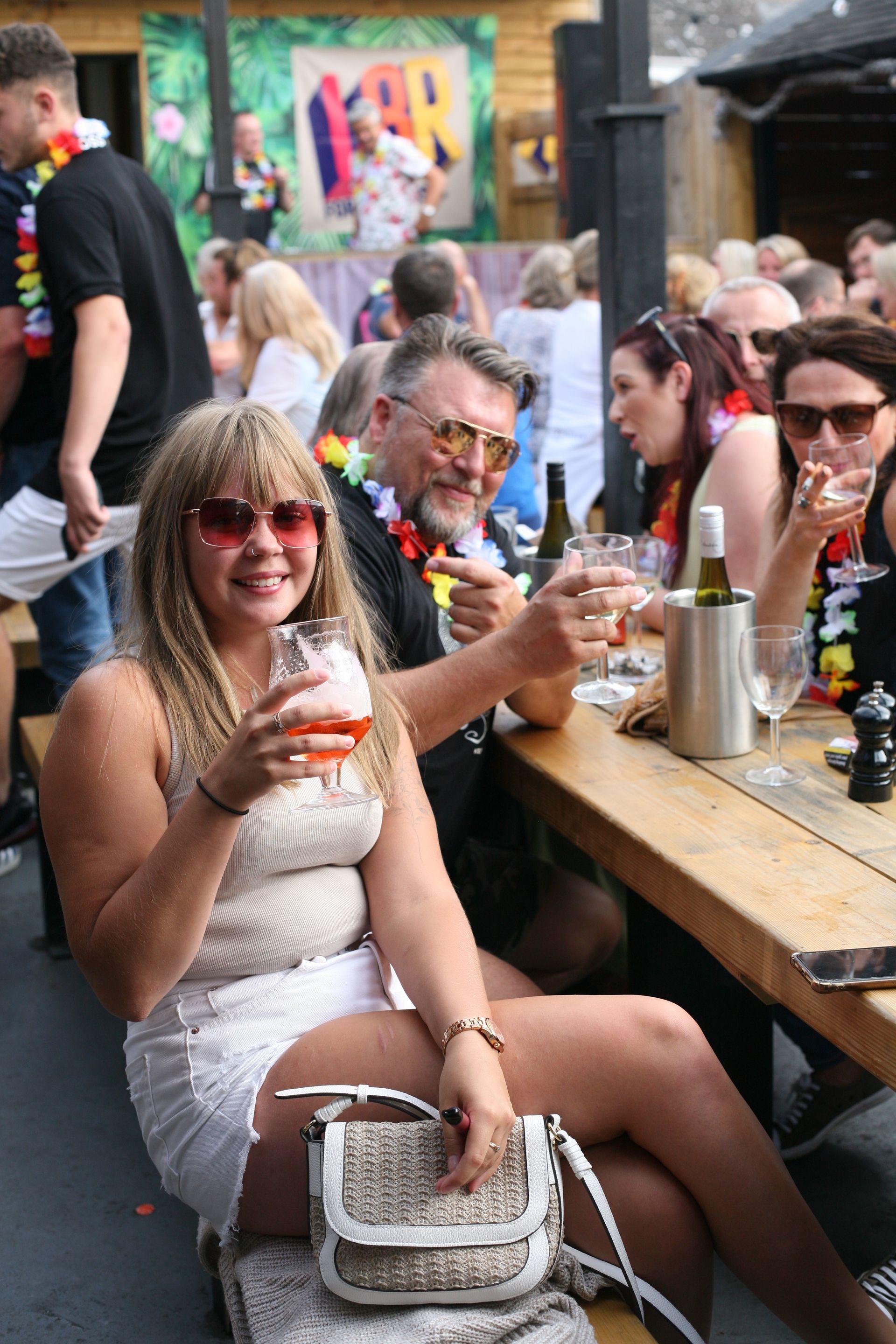 A woman is sitting at a table holding a glass of wine.