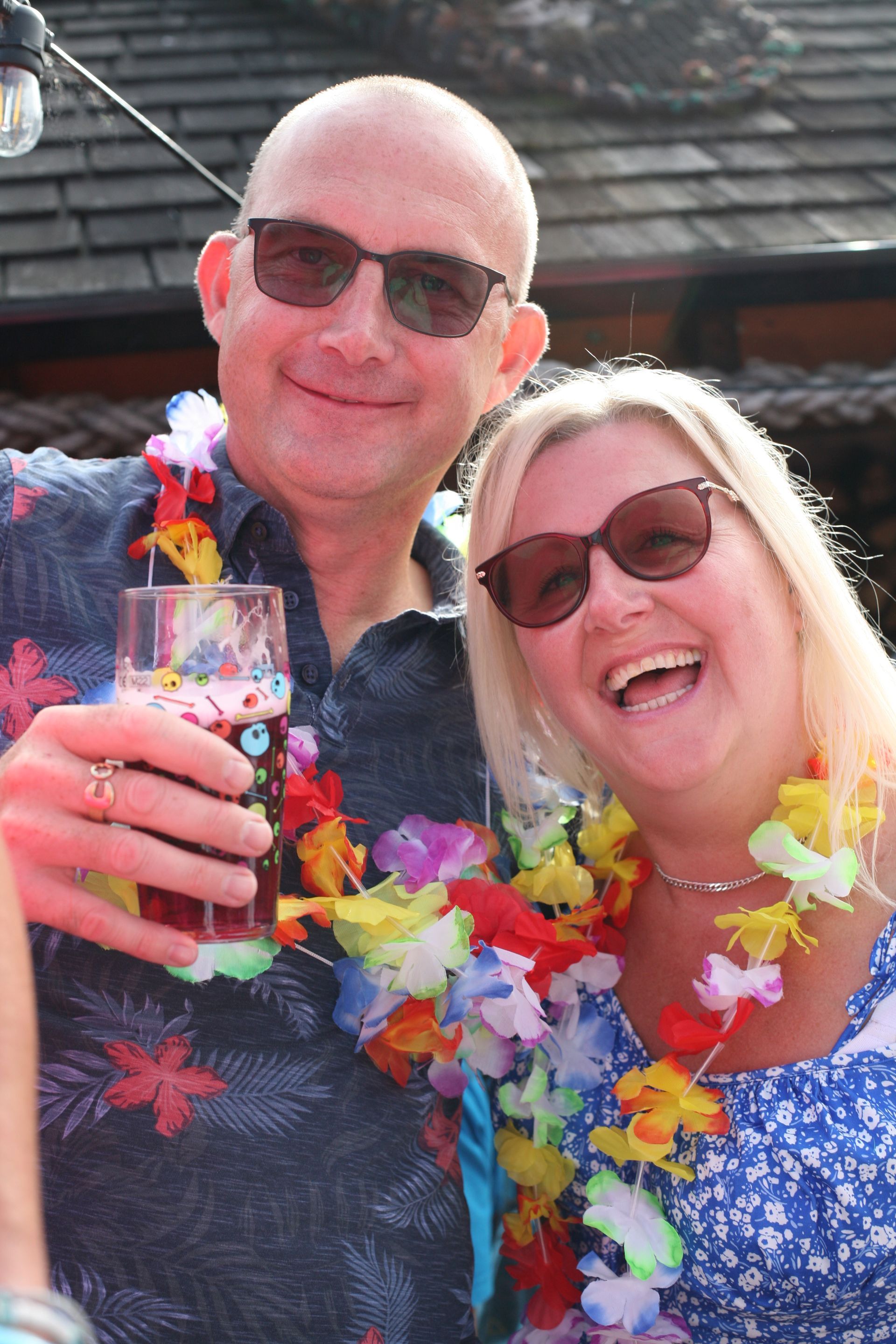 A man and a woman are posing for a picture while holding drinks.