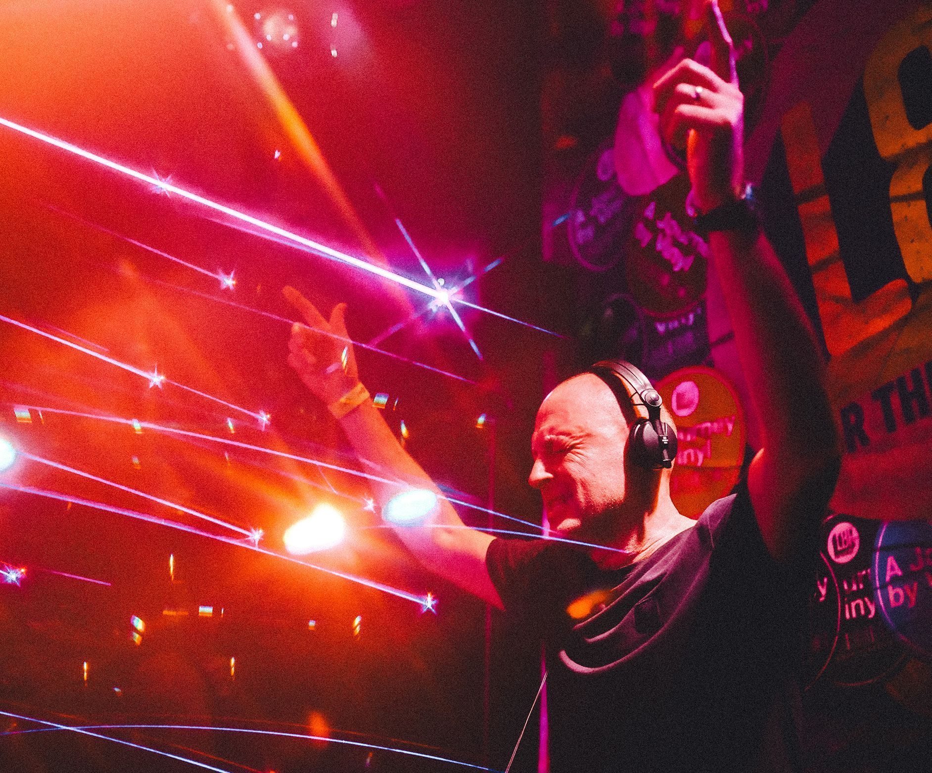 A man wearing headphones stands in front of a sign that says ' r the ' on it