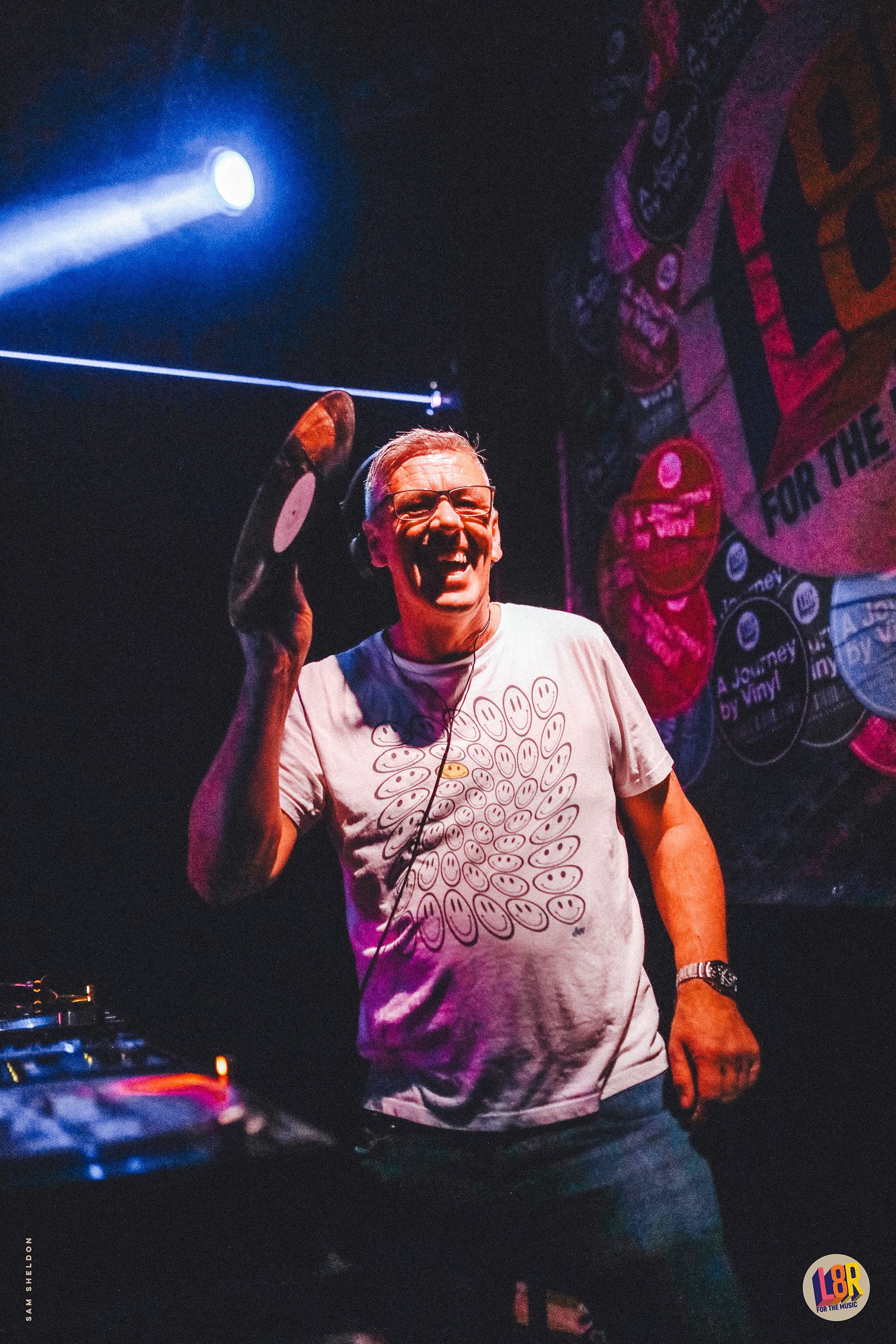 A man in a white shirt is singing into a microphone on a stage.