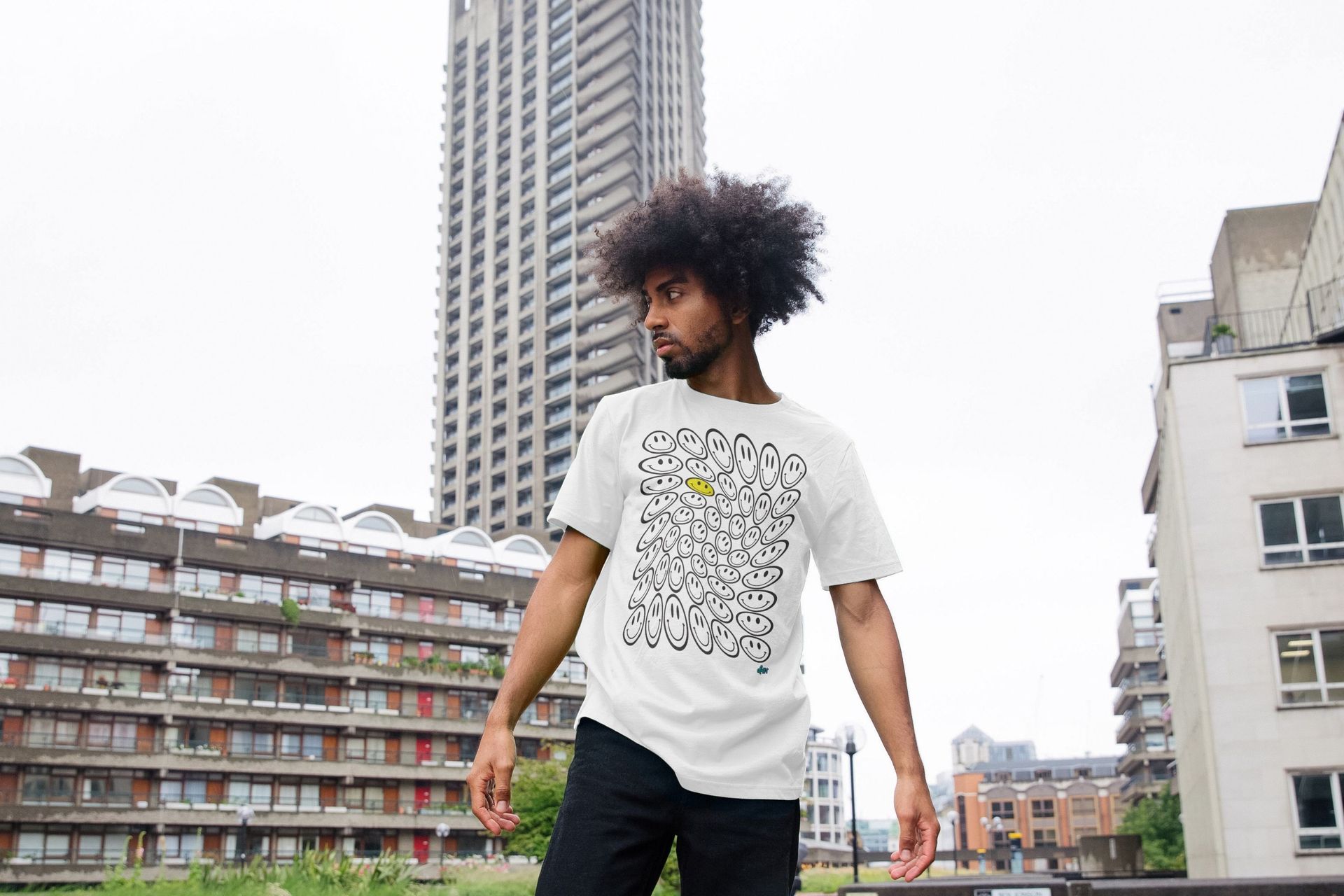 A man wearing a white t-shirt is standing in front of a tall building.