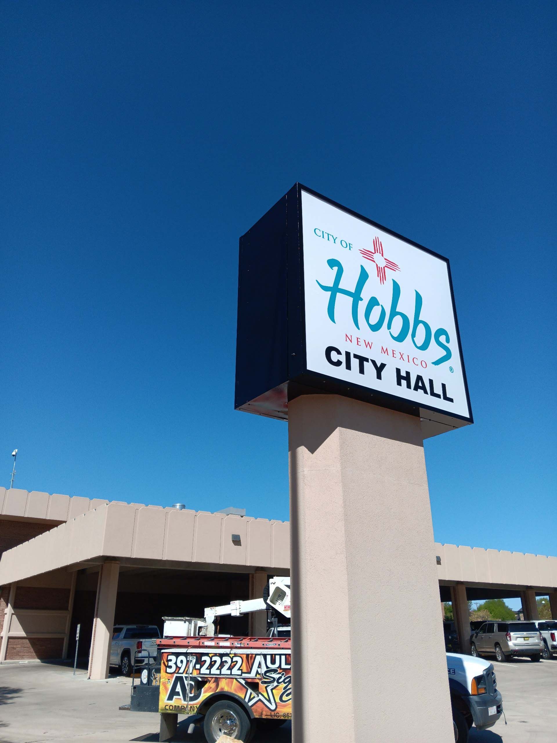A hobbs city hall sign in front of a building