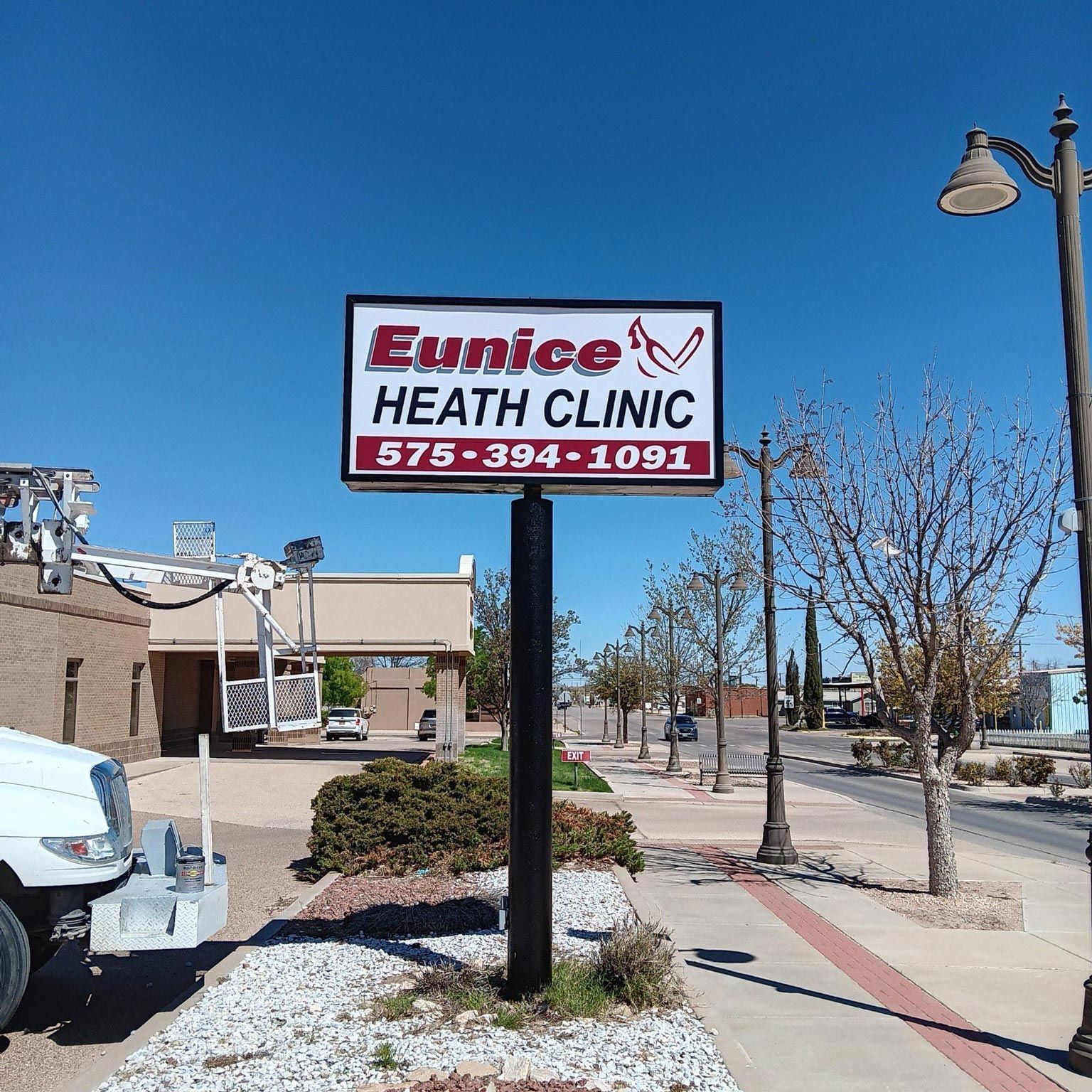 A white truck is parked in front of a eunice heath clinic sign