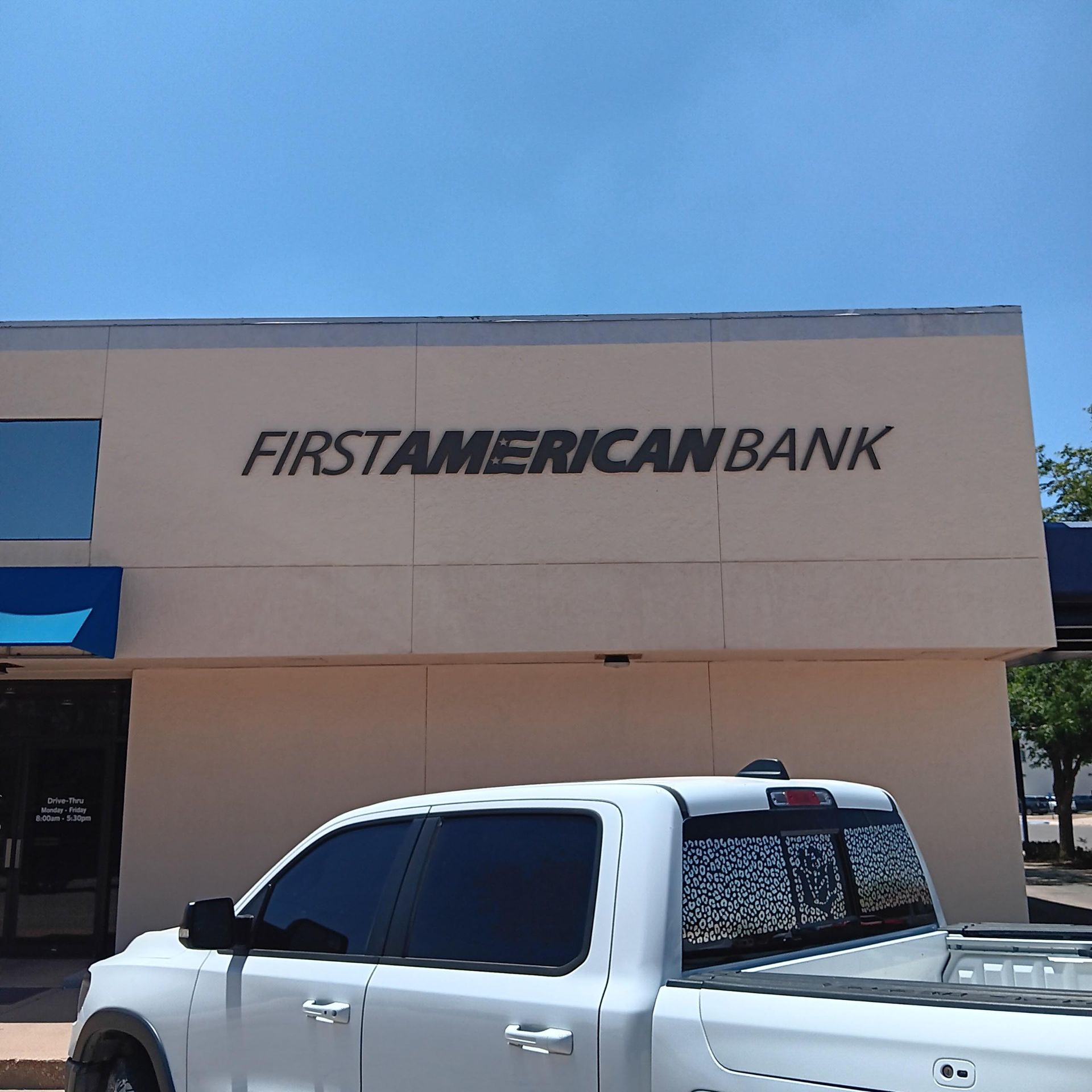 A white truck is parked in front of a first american bank