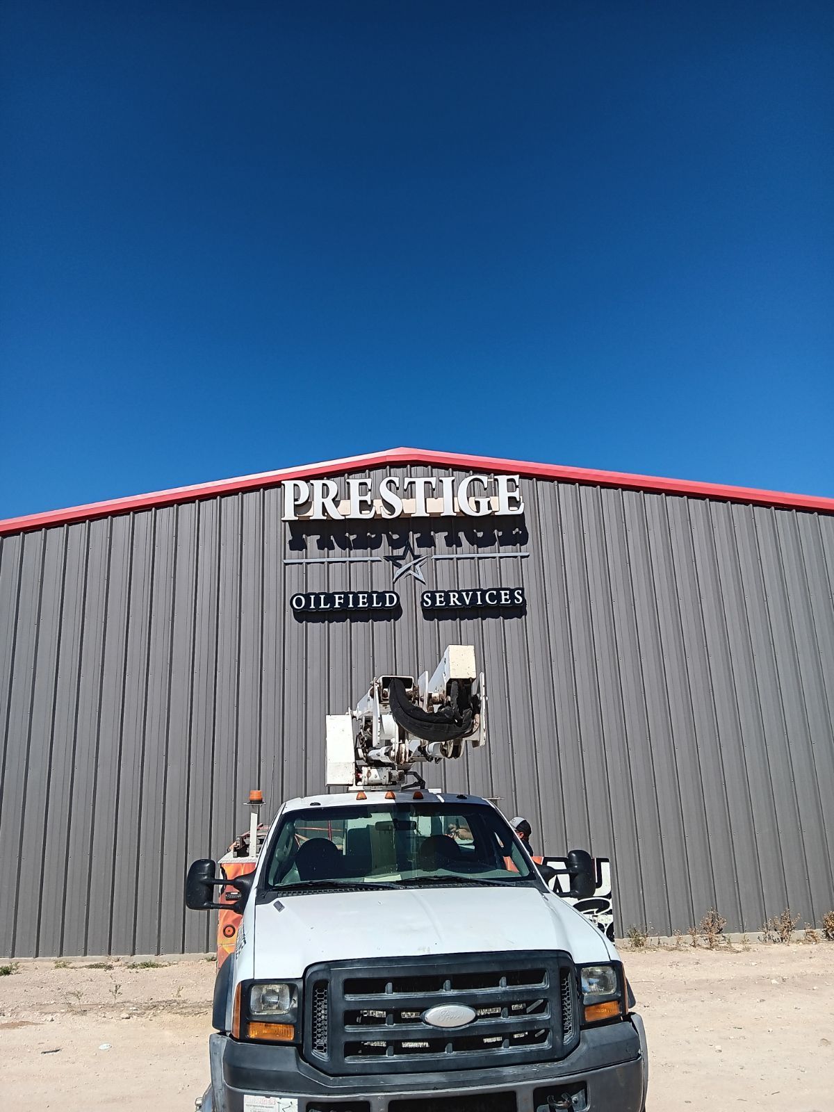 A white truck is parked in front of a building that says prestige