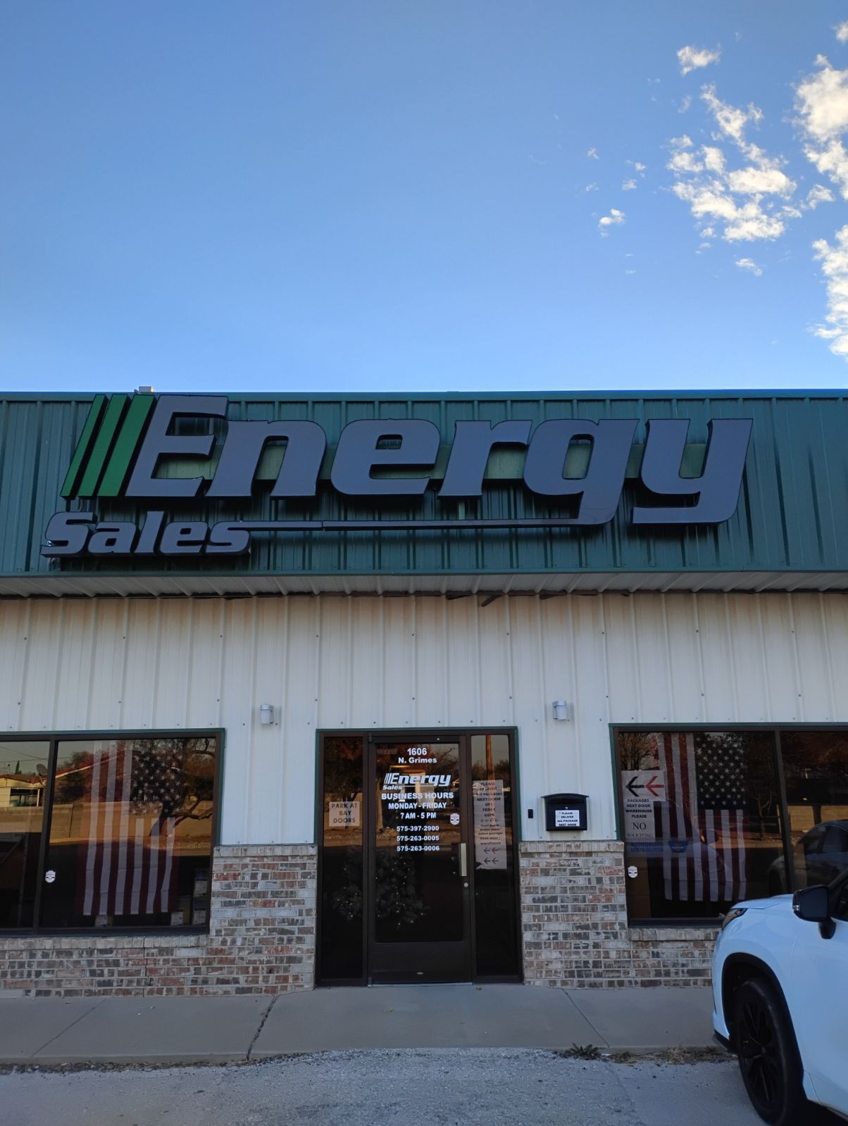 A white truck is parked in front of a building that says energy sales