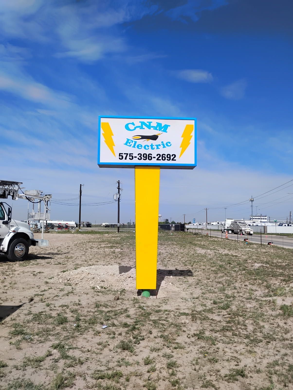 A blue and yellow sign is sitting in the middle of a field.
