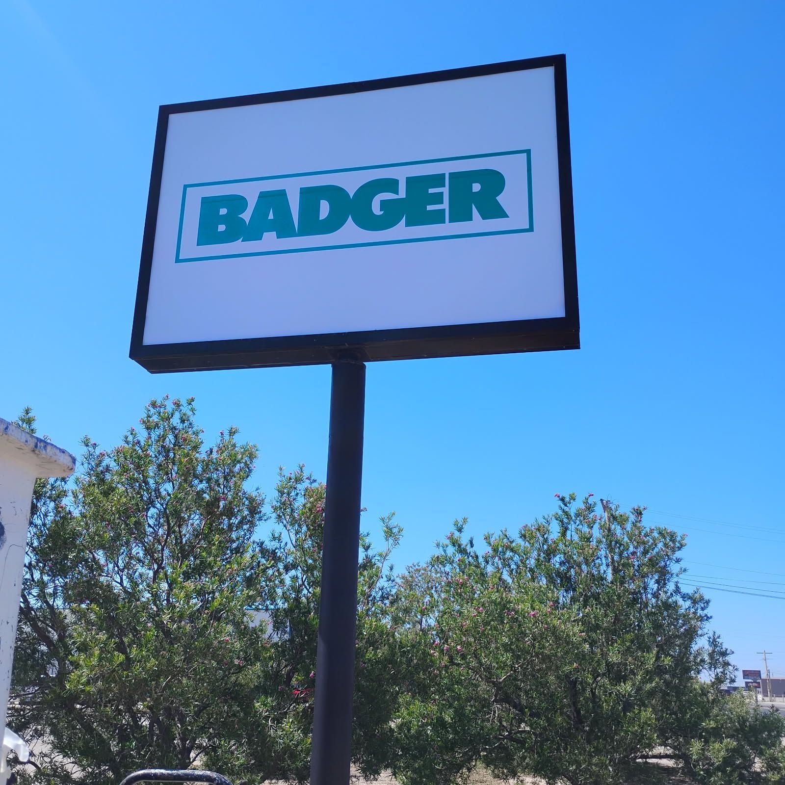 A badger sign that is outside with trees in the background