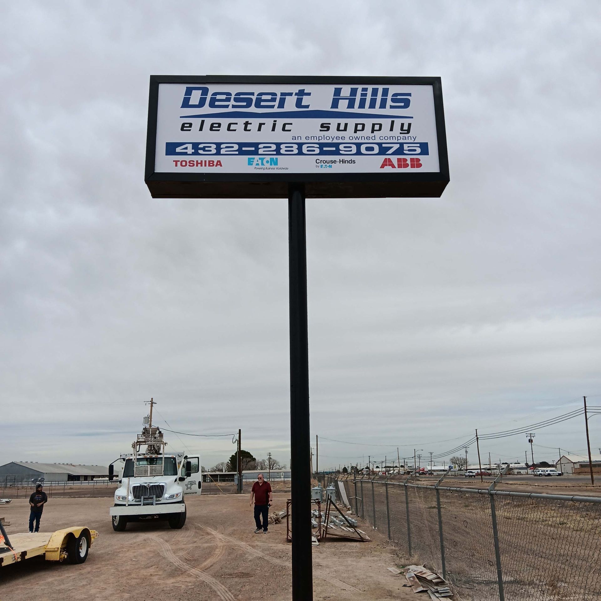 A desert hills electric supply sign in a dirt field