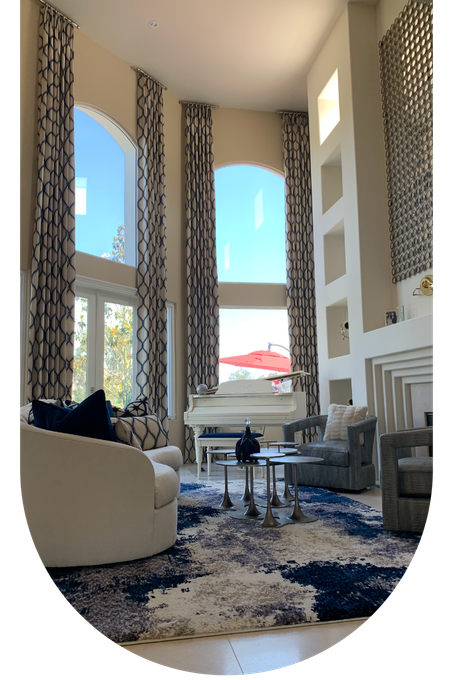 A living room with a piano , chairs , curtains and a rug.