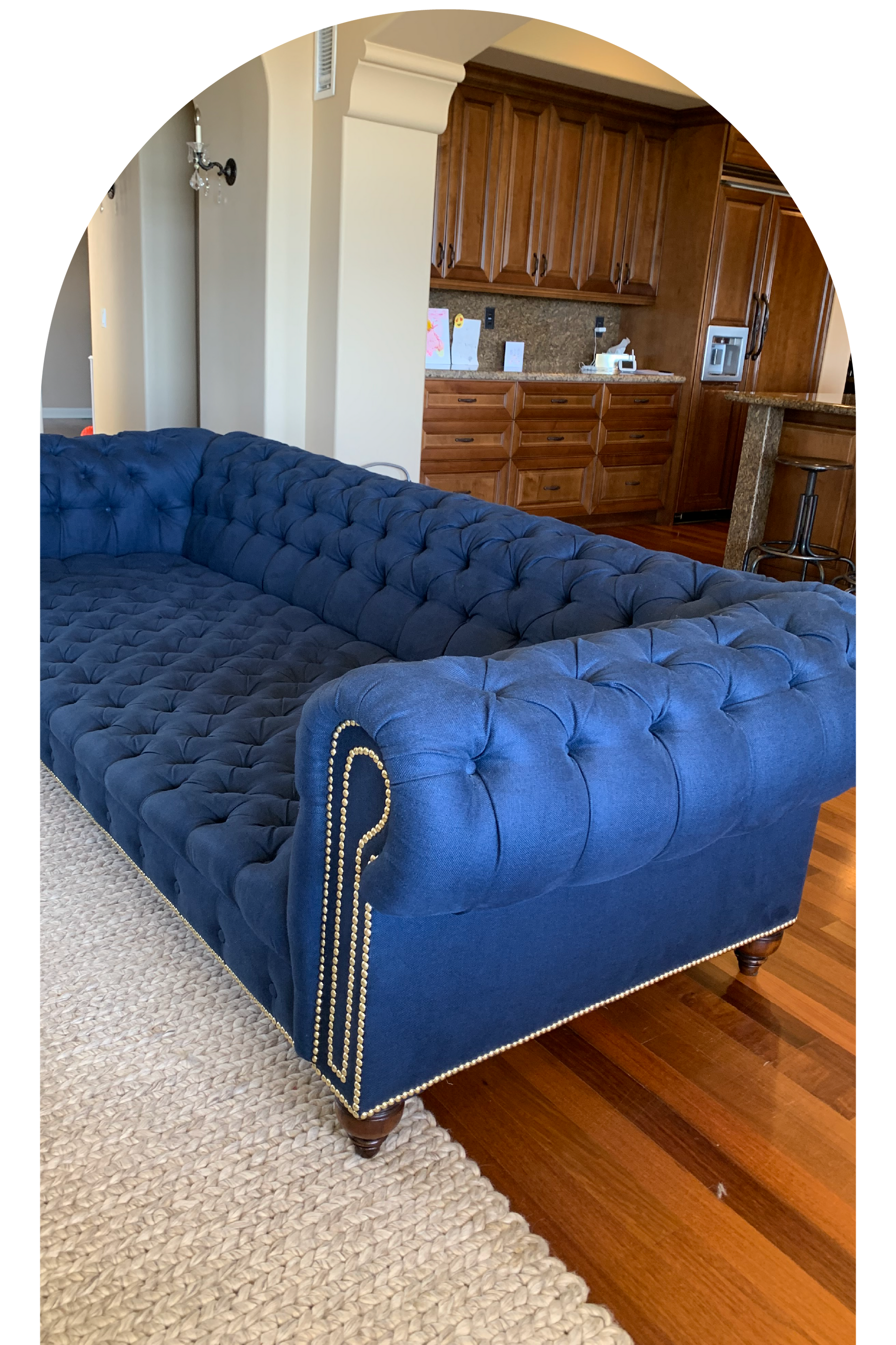 A large blue tufted couch is sitting in a living room.