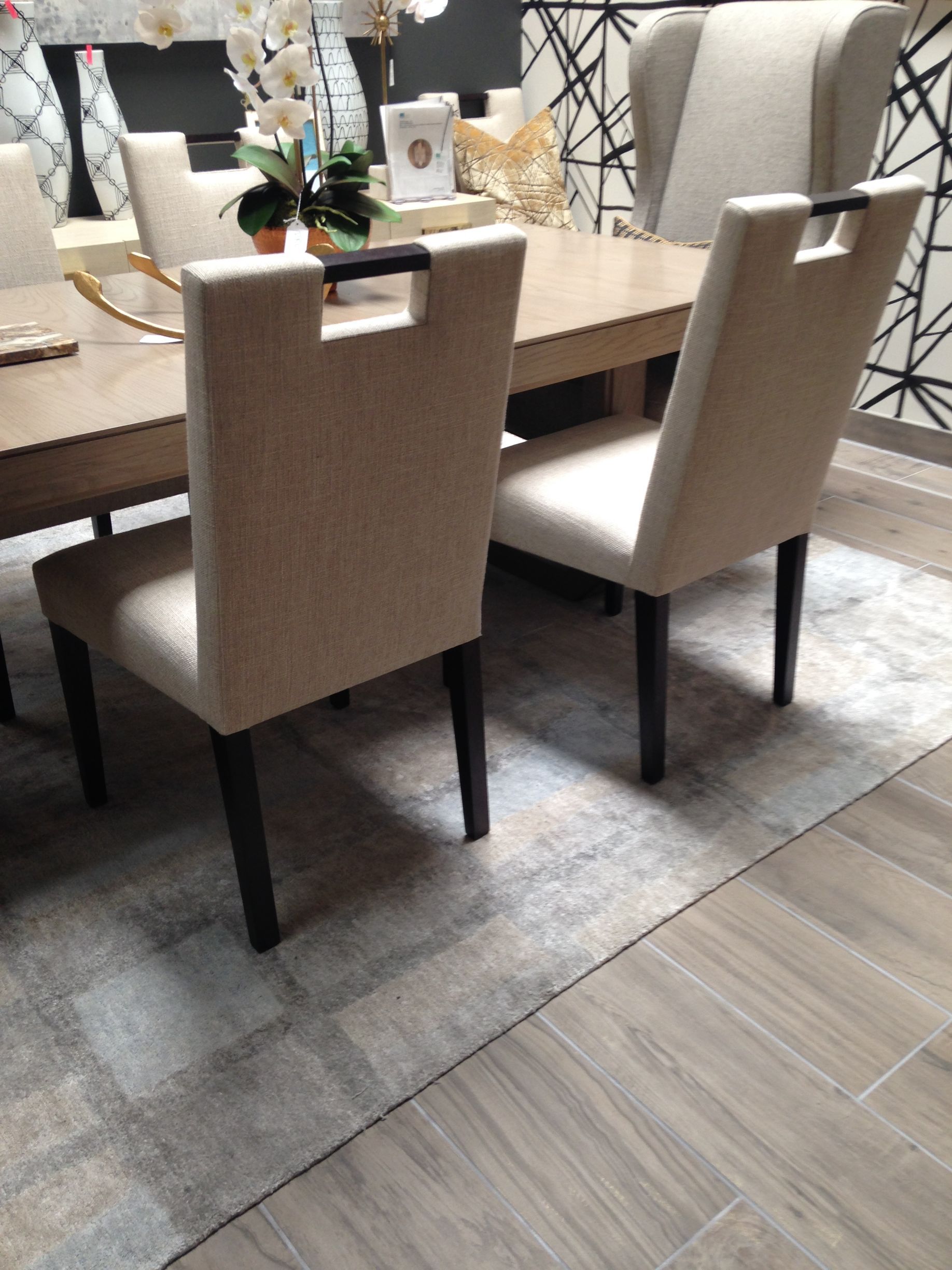 A dining room with a table and chairs and a rug on the floor.