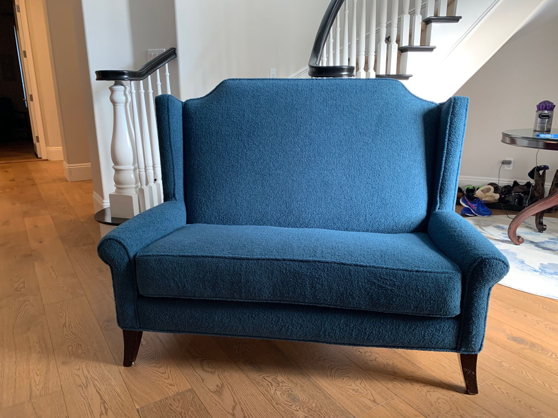 A blue chair is sitting in a living room next to a staircase.