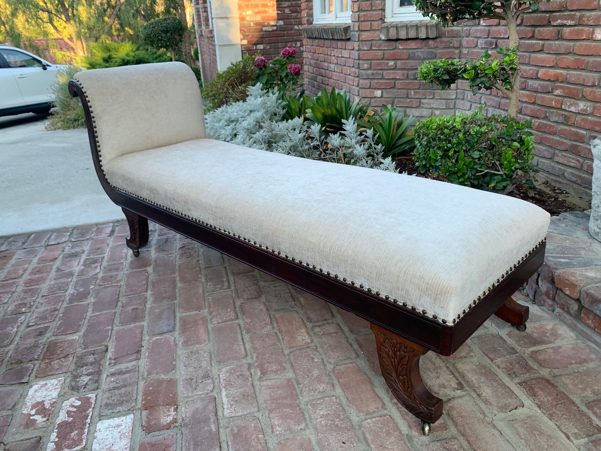 A chaise lounge is sitting on a brick sidewalk in front of a brick building.