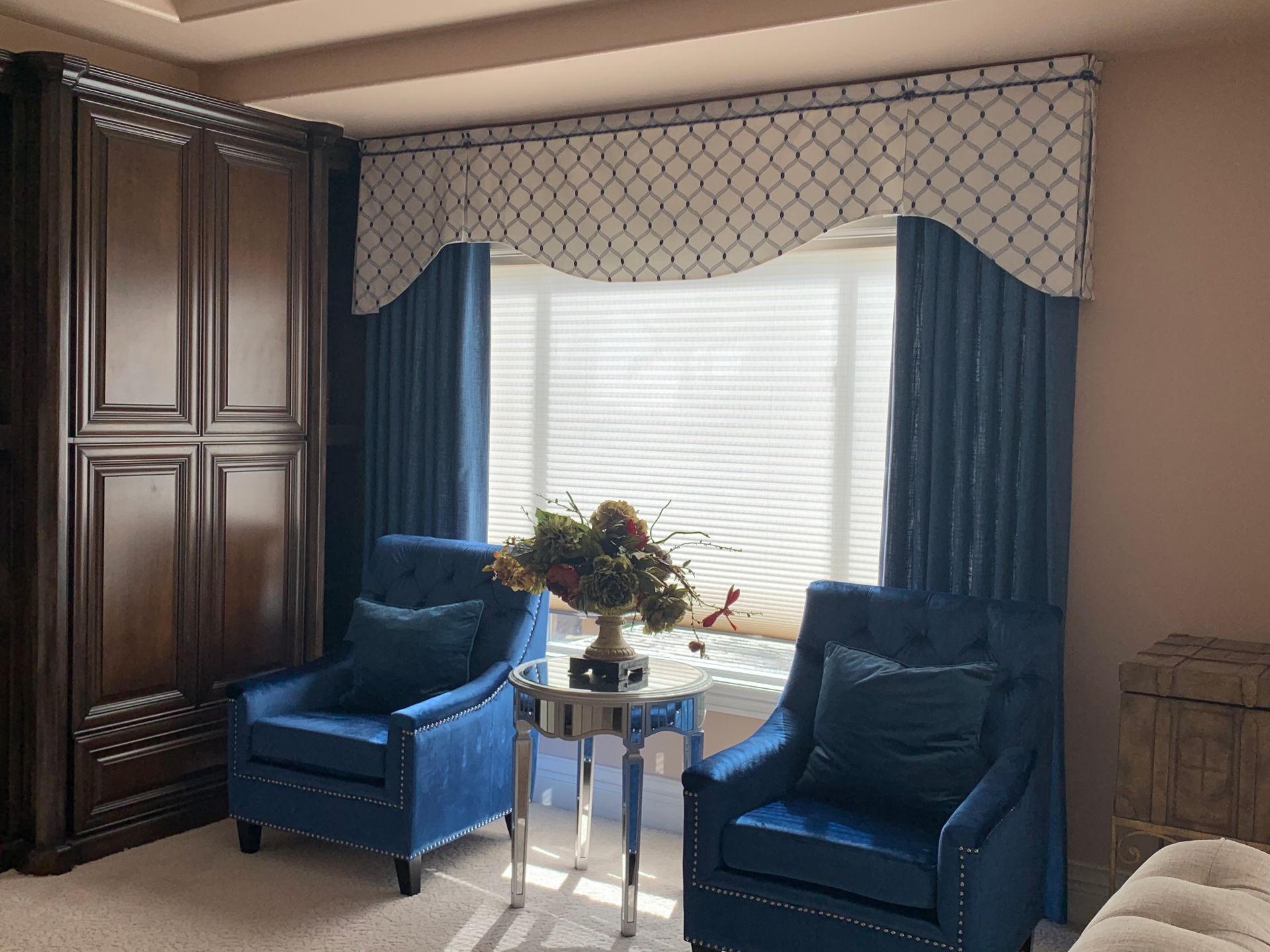 A living room with two blue chairs and a table in front of a window.