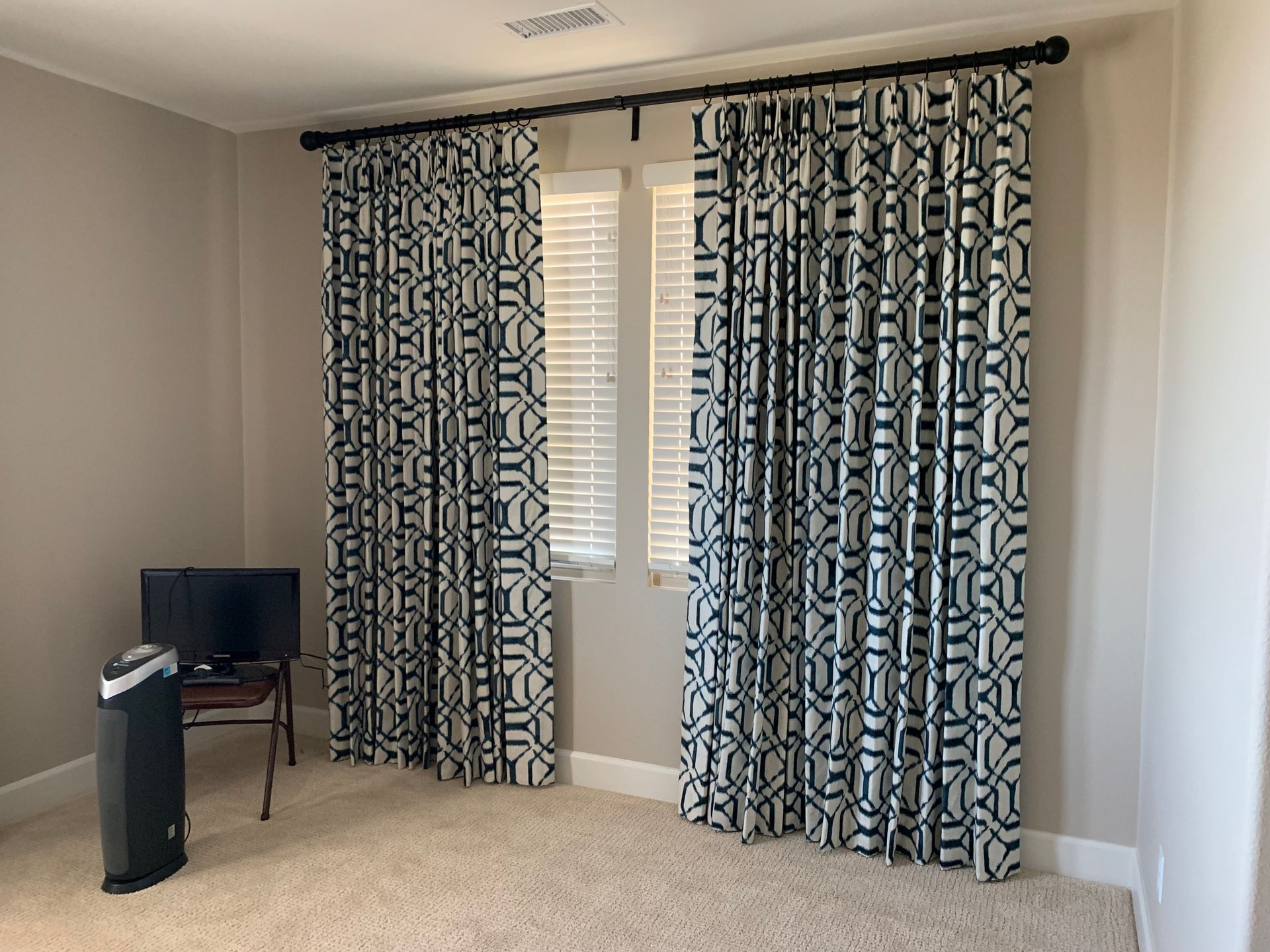 A living room with curtains and a tv on a stand