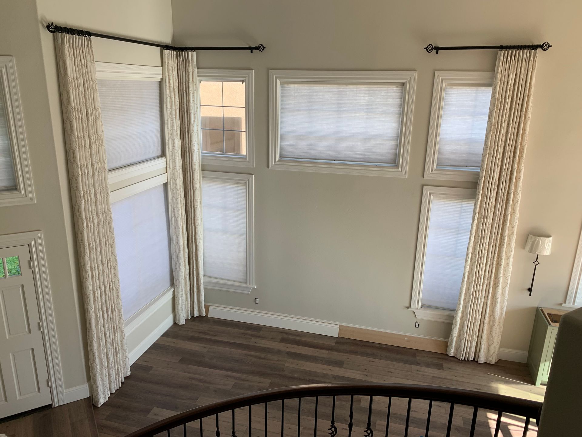 A room with a staircase and lots of windows and curtains.