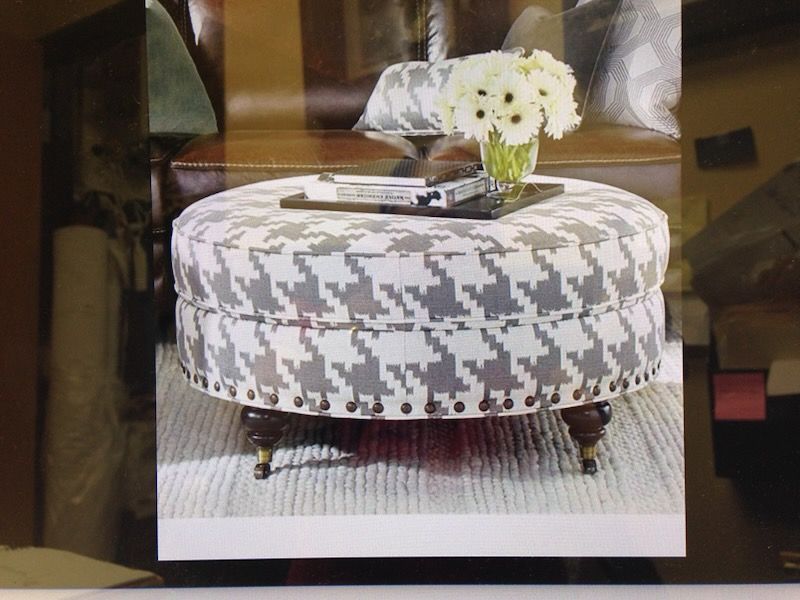 A round ottoman with a vase of flowers on top of it