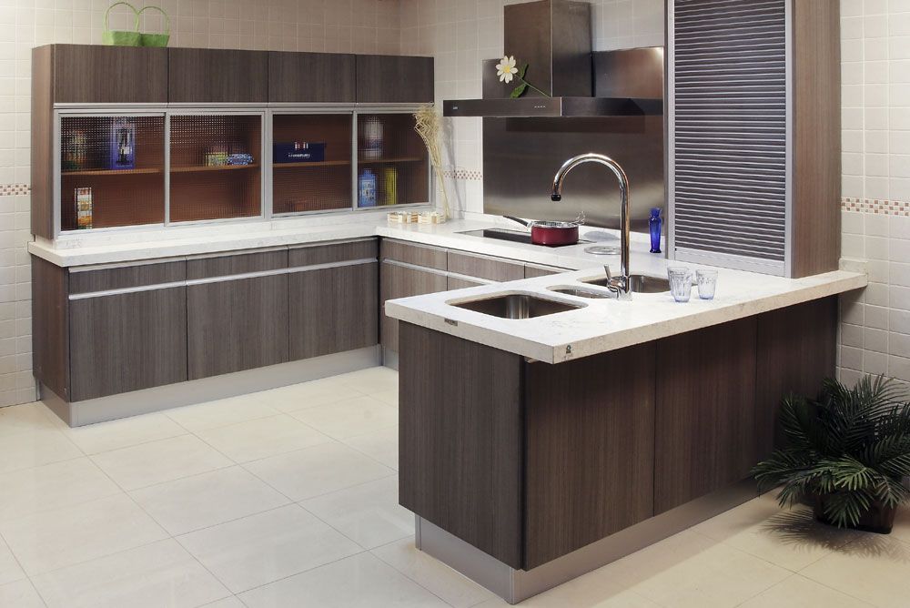 Cocina moderna con gabinetes grises, encimeras blancas y electrodomésticos de acero inoxidable.