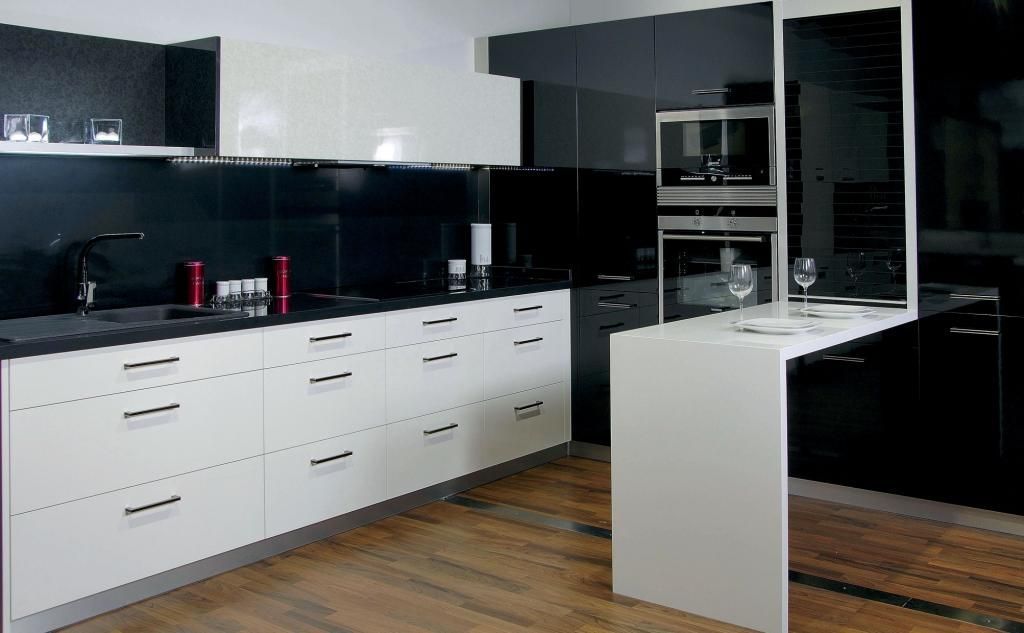 Cocina moderna con gabinetes blancos, protector contra salpicaduras negro y una pequeña barra de desayuno.