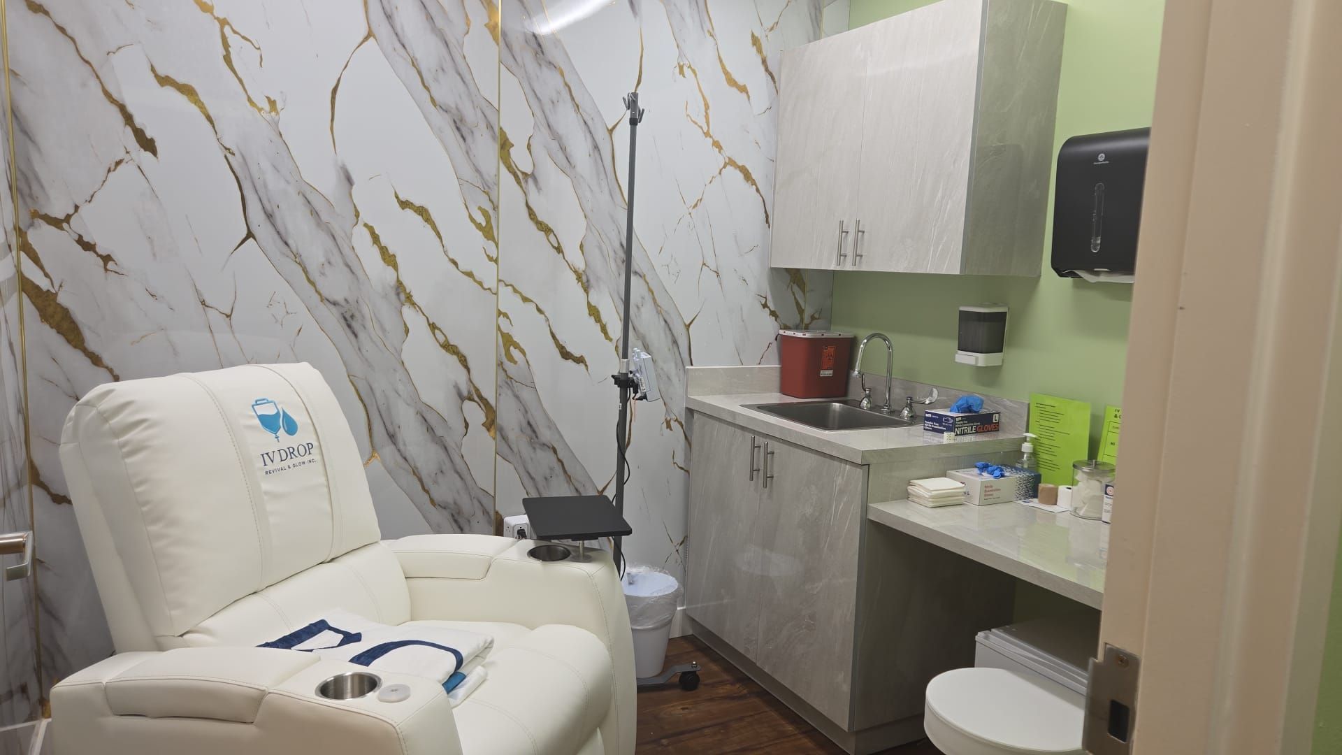 Examination room with a reclining chair, sink, cabinets, and marble wallpaper.