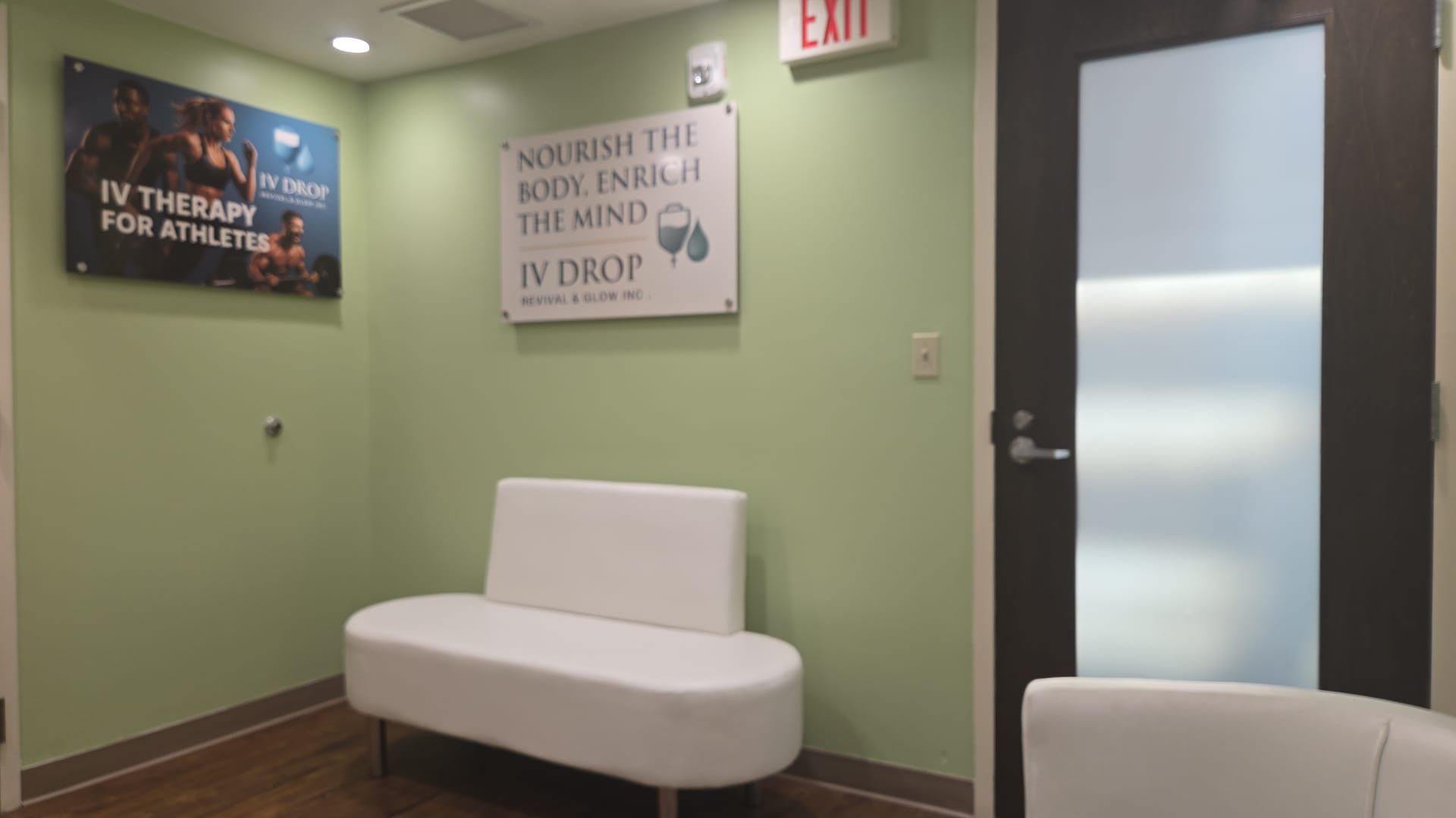 Waiting room with a white bench, green walls, and signs for IV therapy.