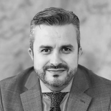 A man in a suit and tie is smiling in a black and white photo.