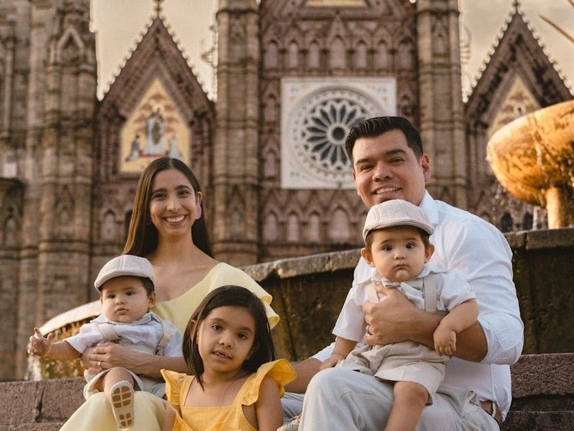 A family is posing for a picture in front of a cathedral.