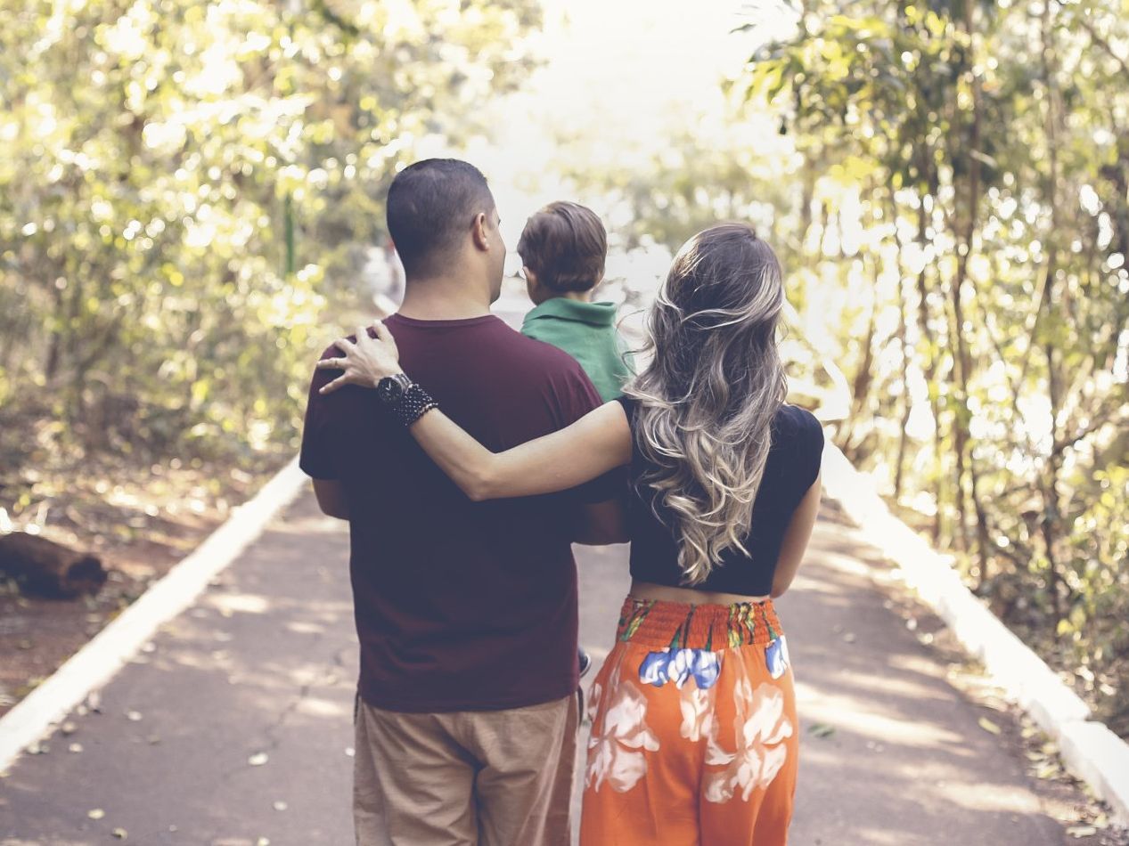 A man and a woman are walking down a road with a child.