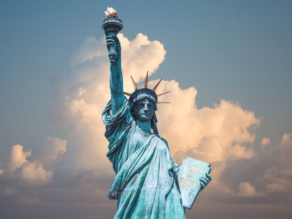 The statue of liberty is standing in front of a cloudy sky.