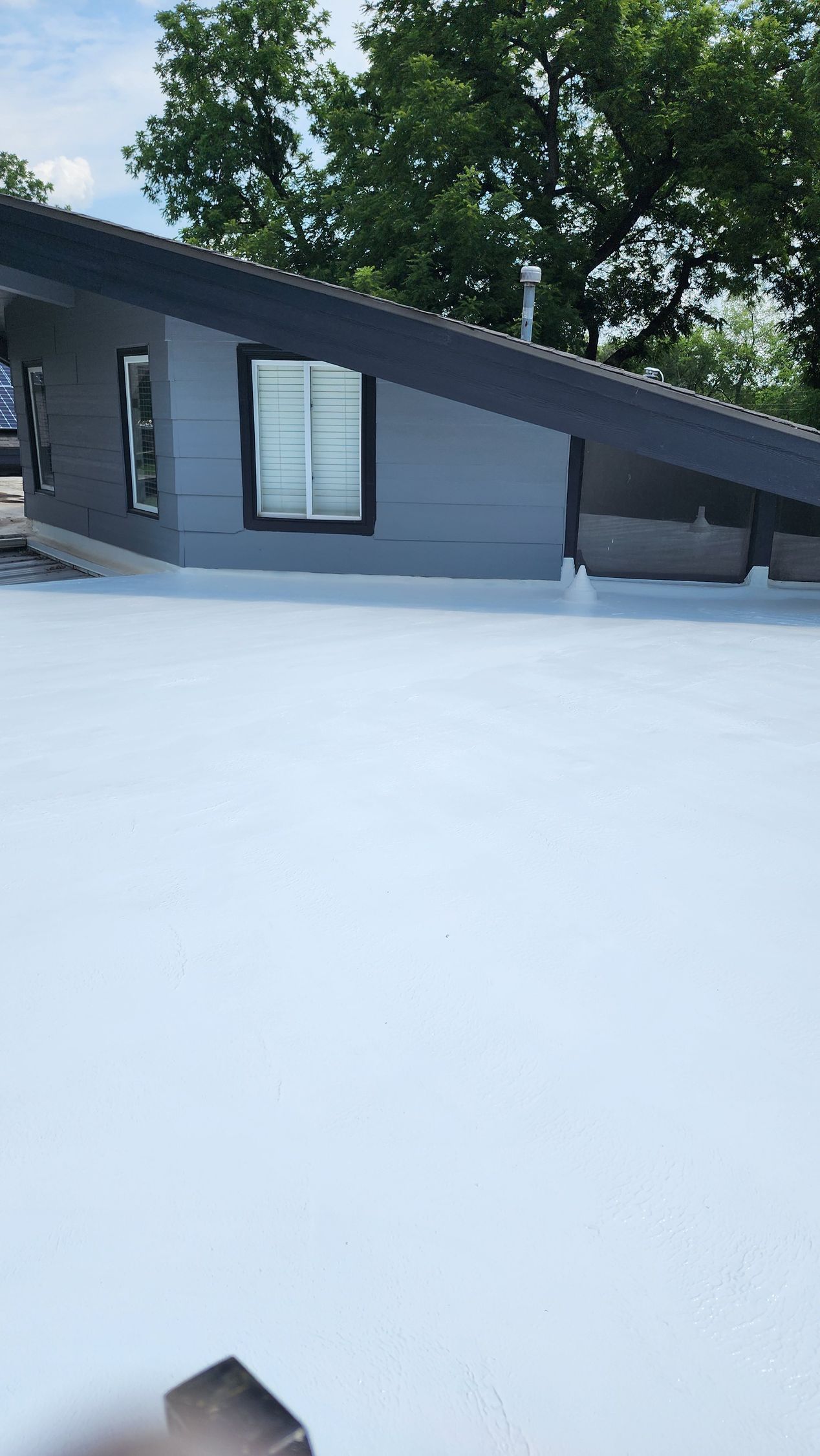 A house with a white roof and trees in the background.