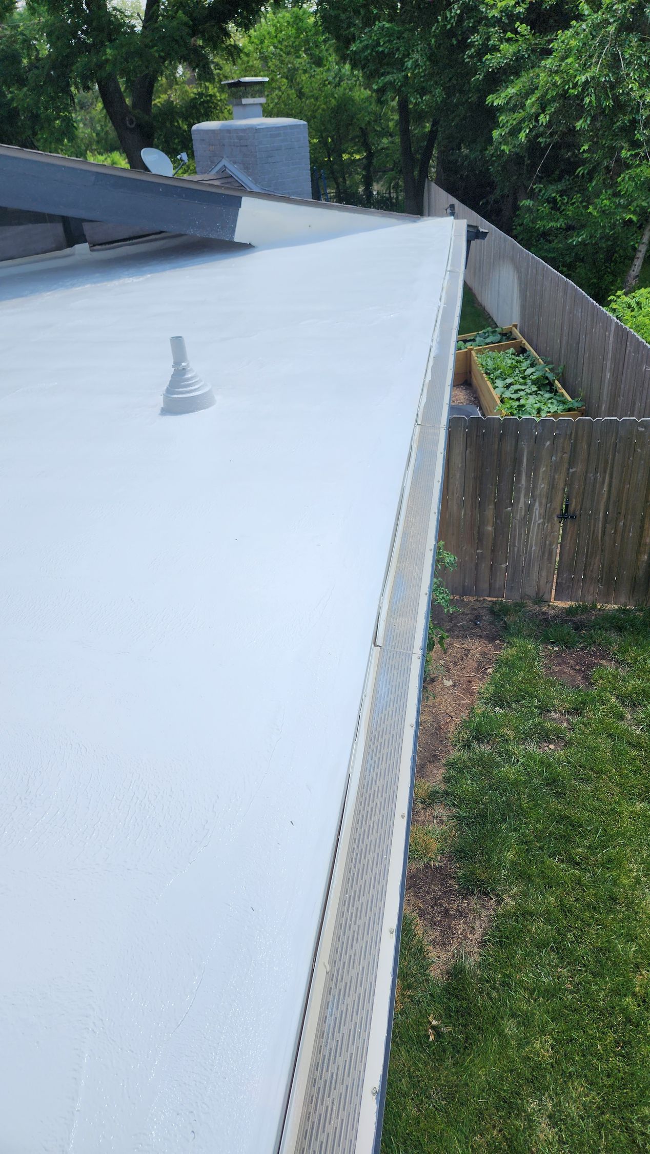 A white roof with a gutter on it and a chimney on top of it.