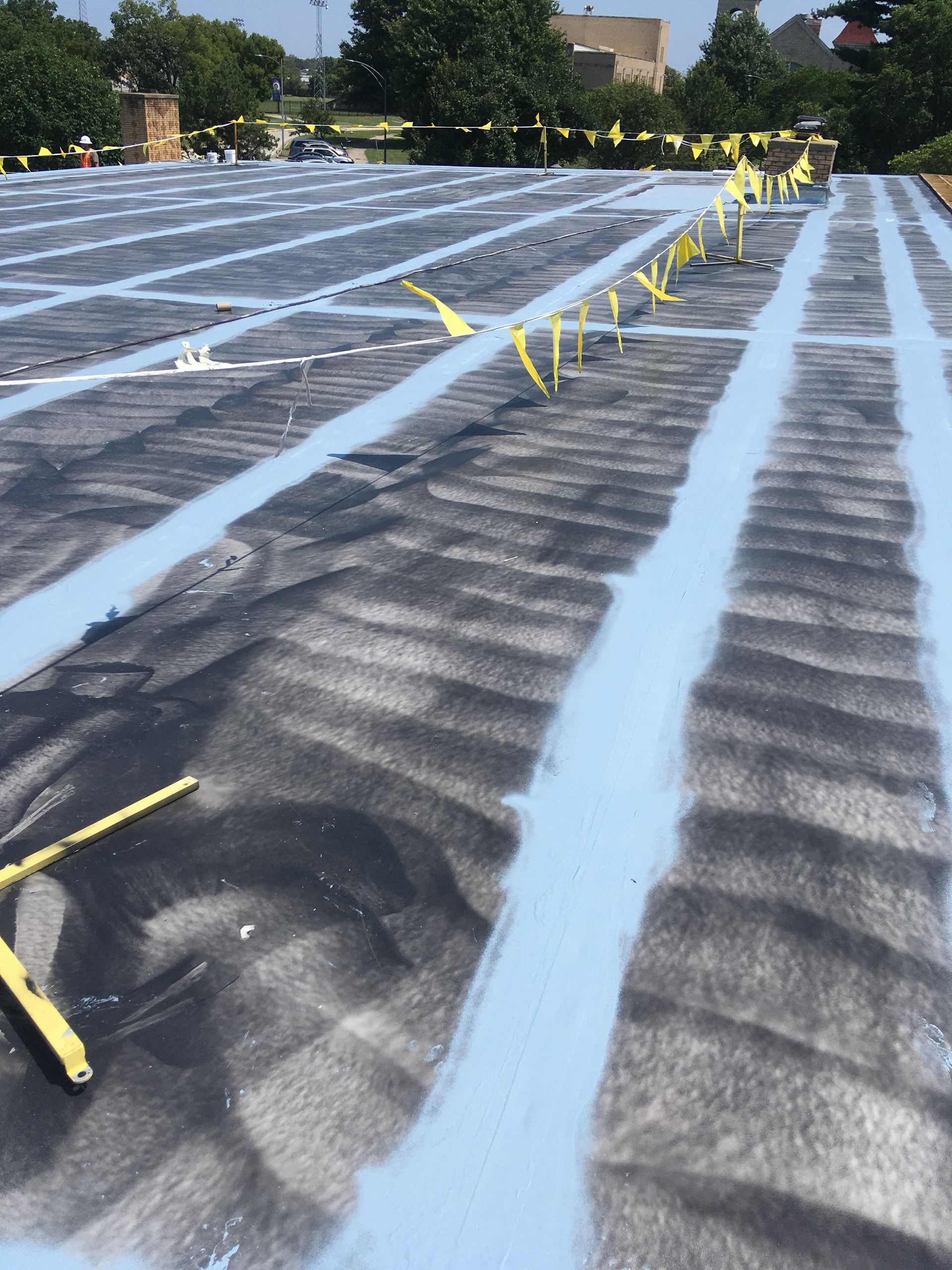 A roof that is being painted with blue paint