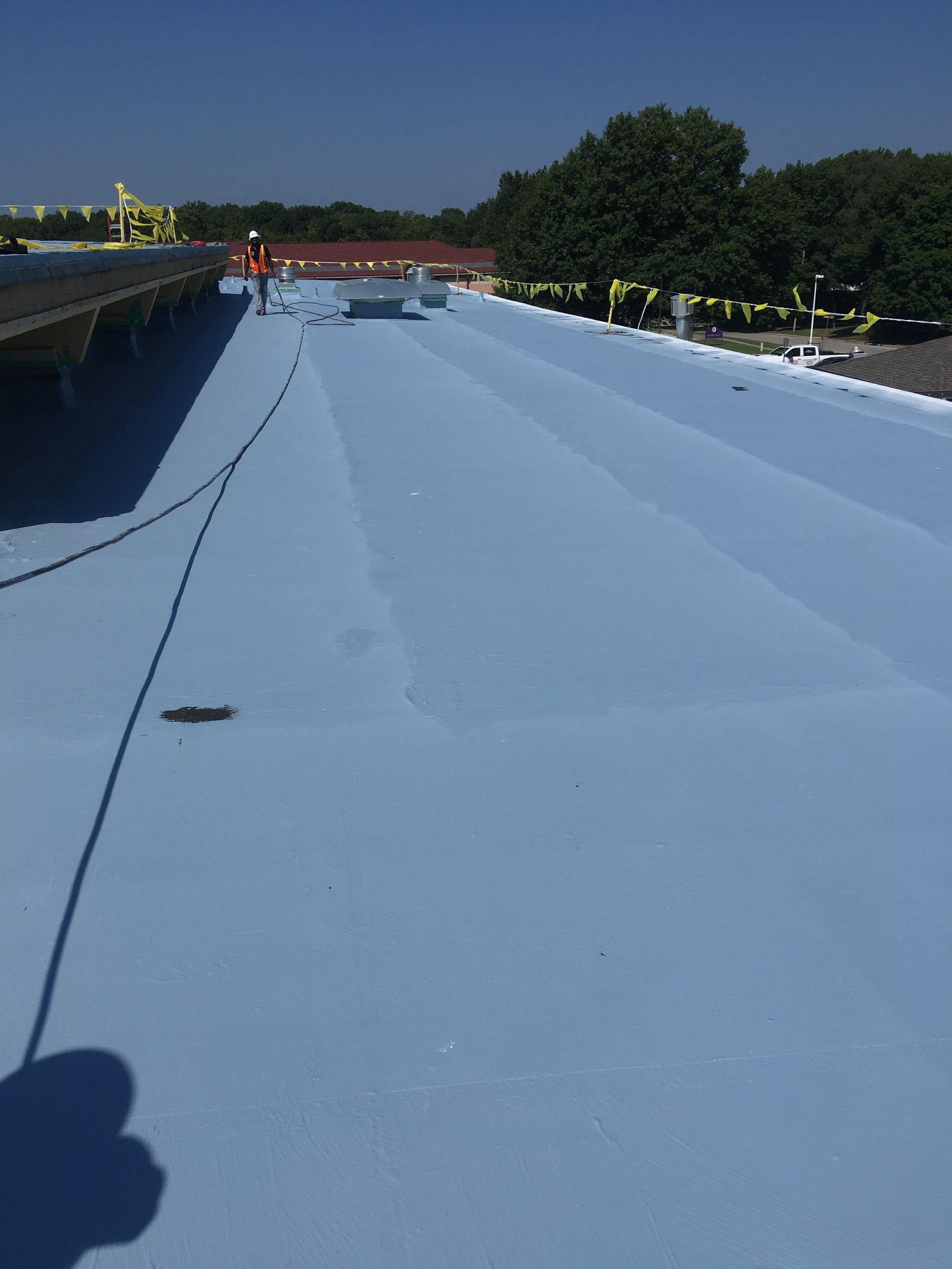A person is standing on top of a blue roof