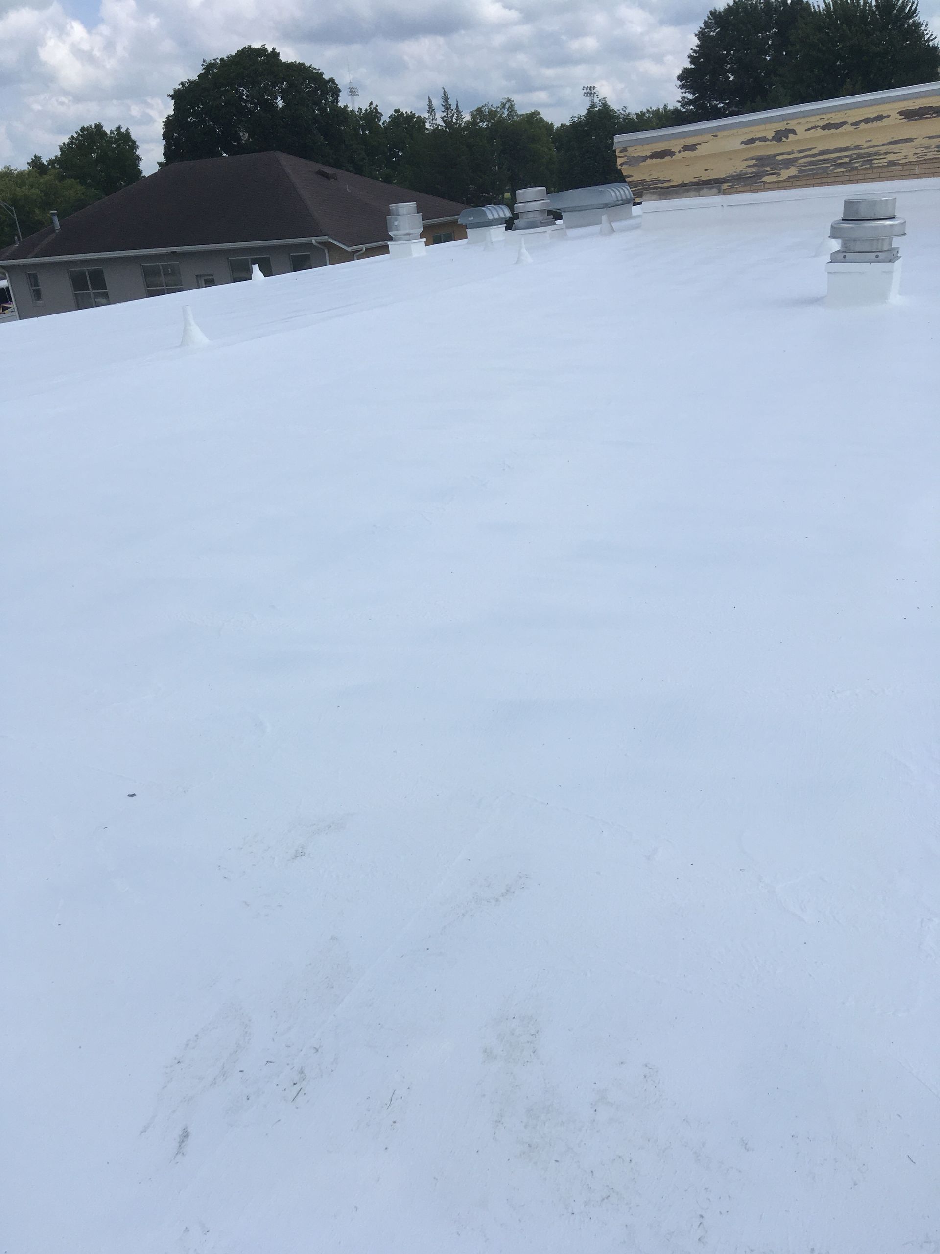 A white roof with a few houses in the background.