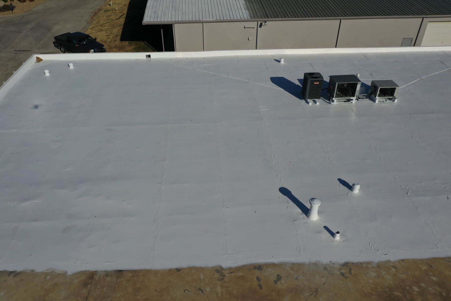 An aerial view of a white roof with air conditioners on it.
