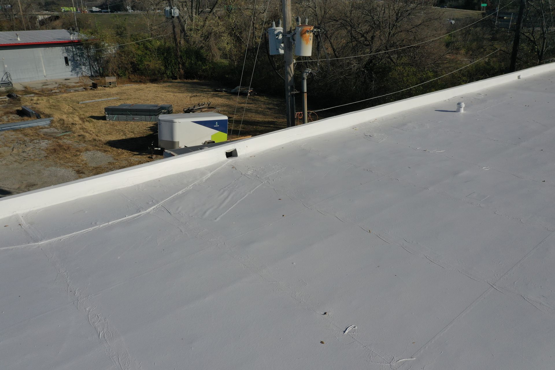 A white roof with a few trees in the background.