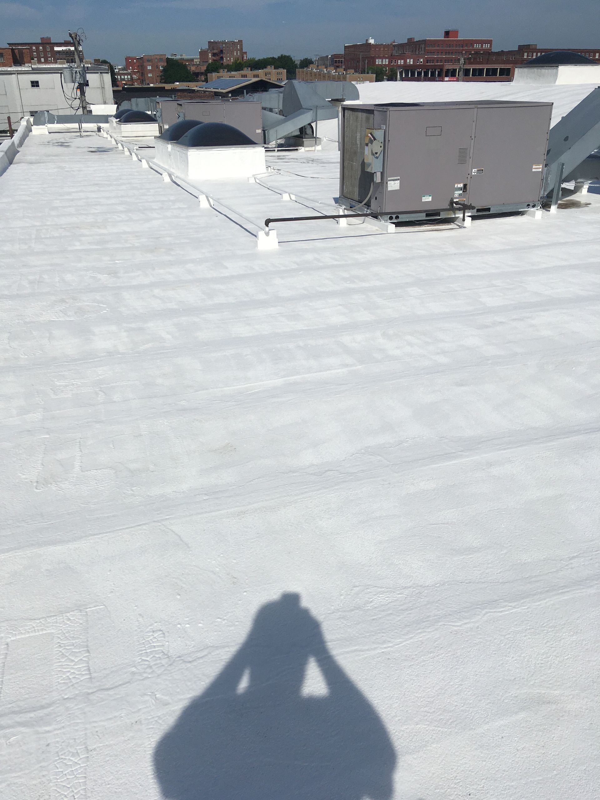 A shadow of a person is cast on a white roof