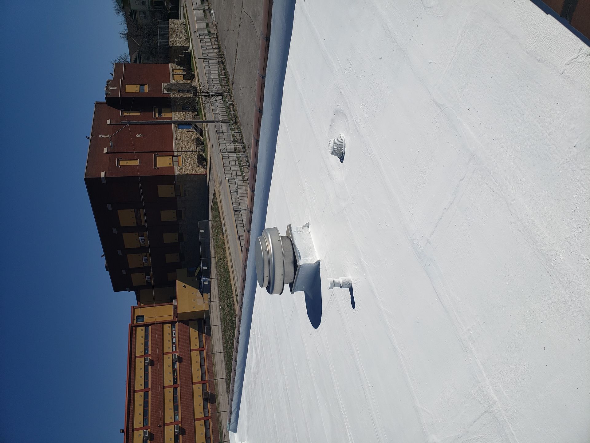 A white roof with a brick building in the background