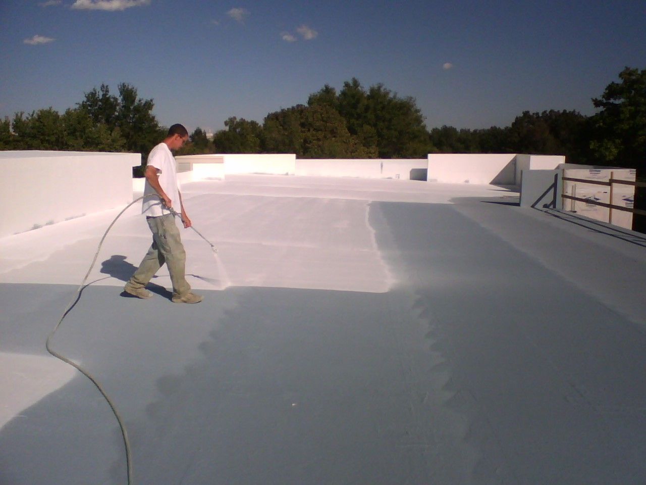 A man is spraying a roof with a hose