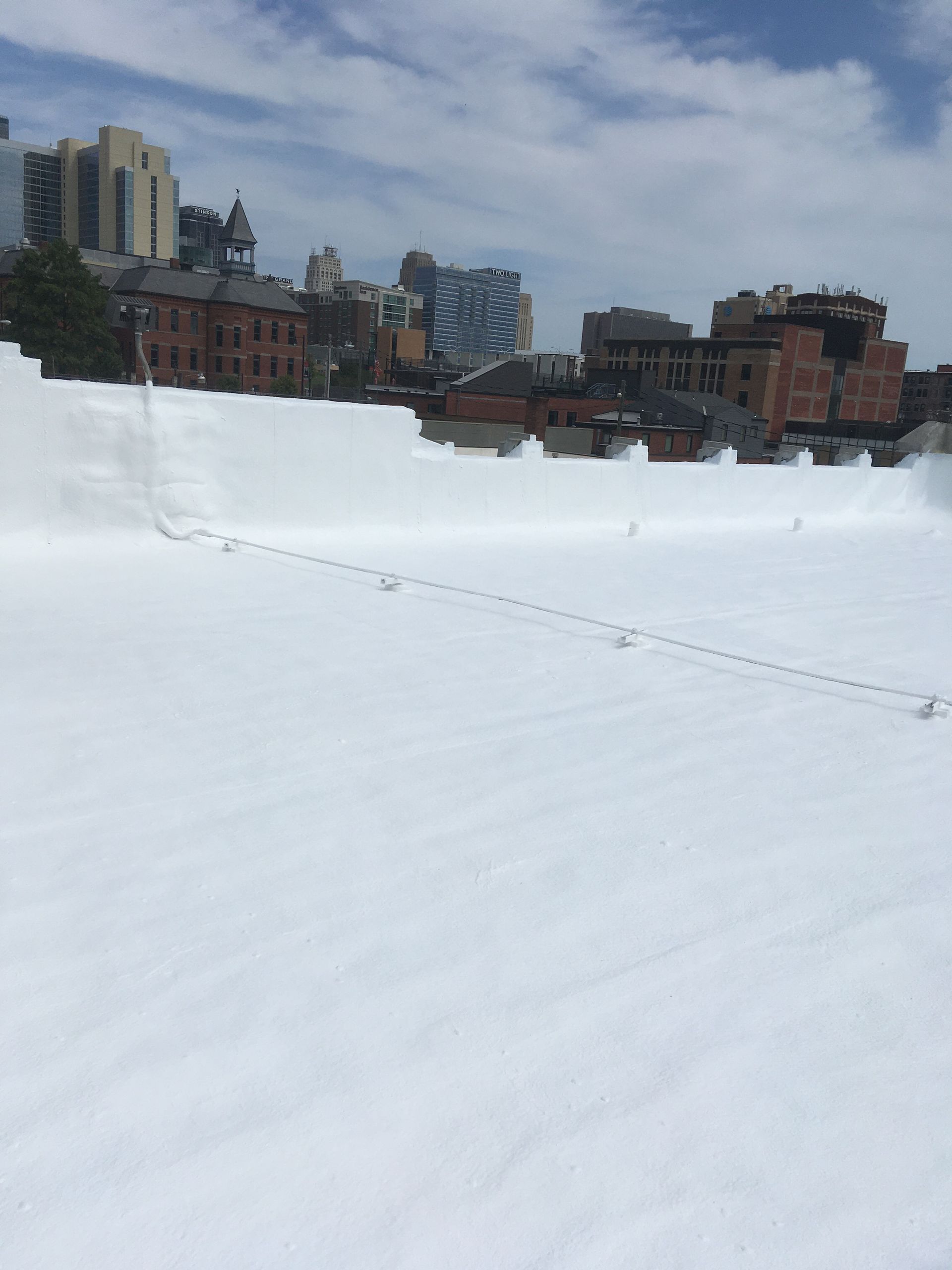 A snowy roof with a city skyline in the background