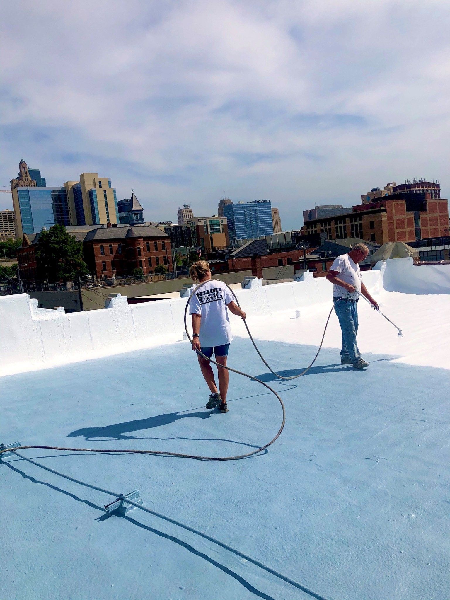 Two people are standing on a blue roof with a city in the background