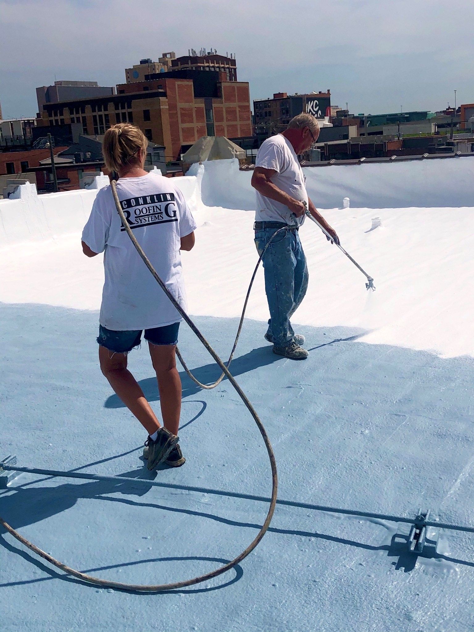 A man and a woman are painting a blue roof